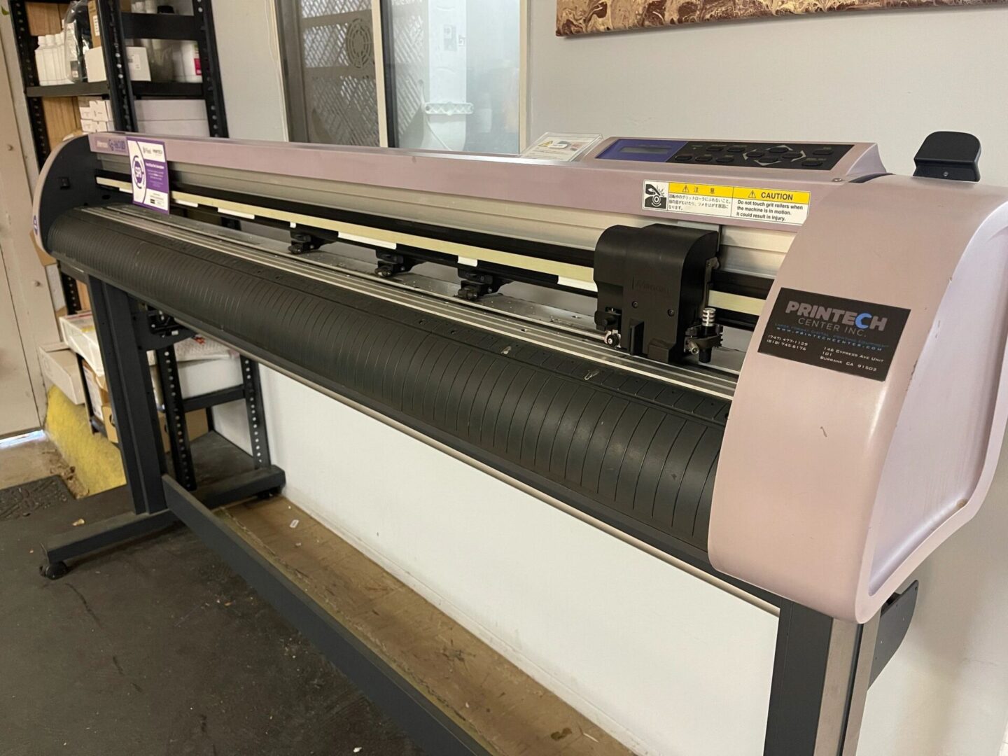 A large pink and black printer sitting in front of a wall.