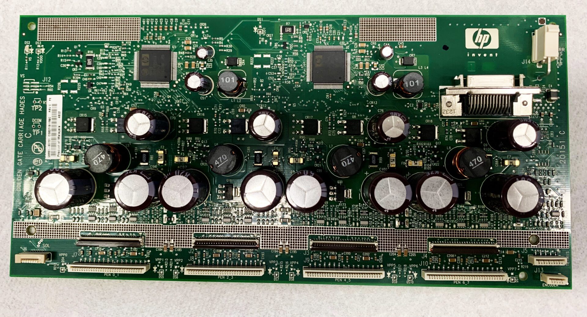 A green circuit board with many buttons and wires.